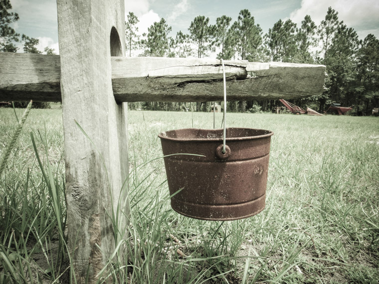 Rusty bucket hanging from wooden fence at Agricultural museum