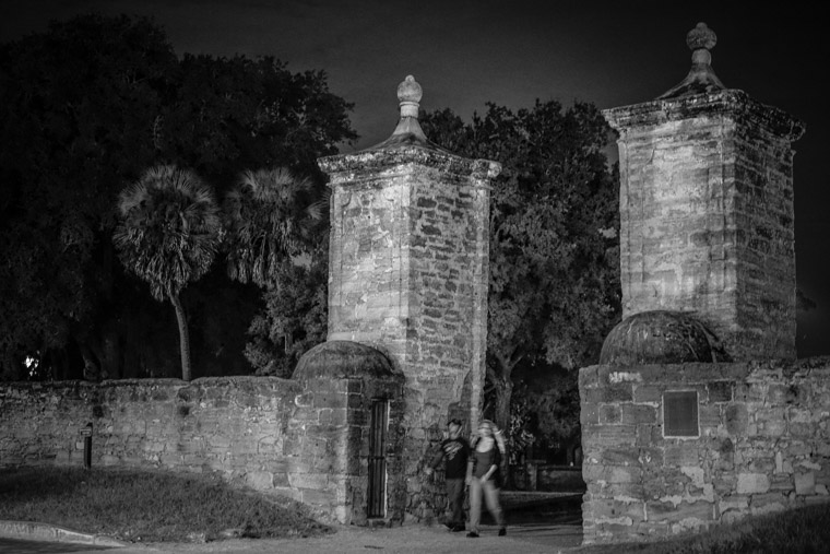 City gates couple walking at night