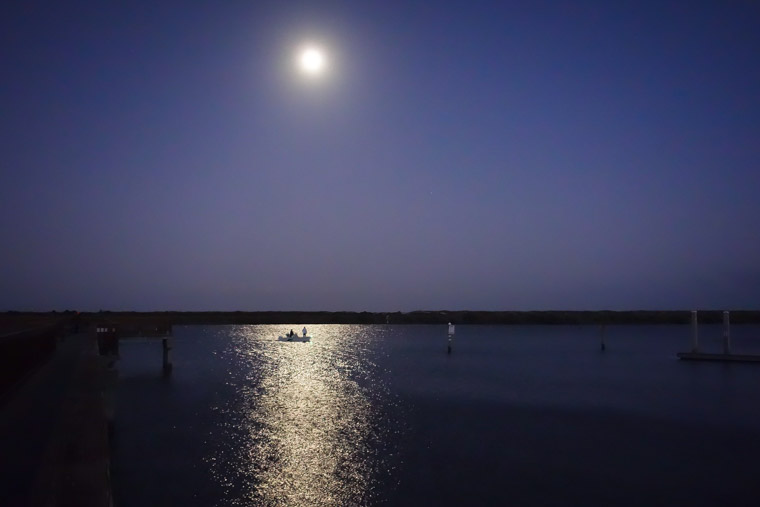 Fishing from boat at night by dock